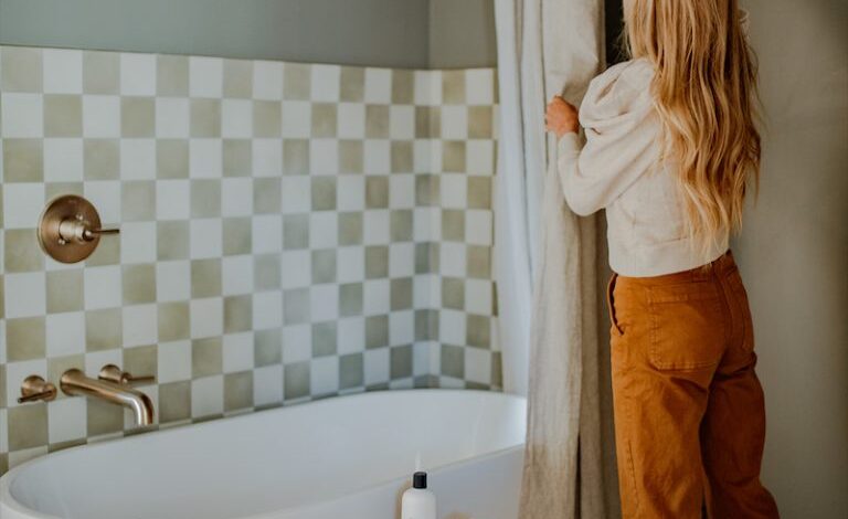 Woman stringing shower curtain in quirky, modern bathroom.
