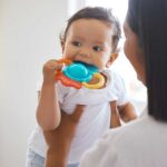 mother with baby biting a teething ring