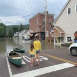 People stand and assess flood damage on Elm Street in Waterbury on Tuesday morning.

