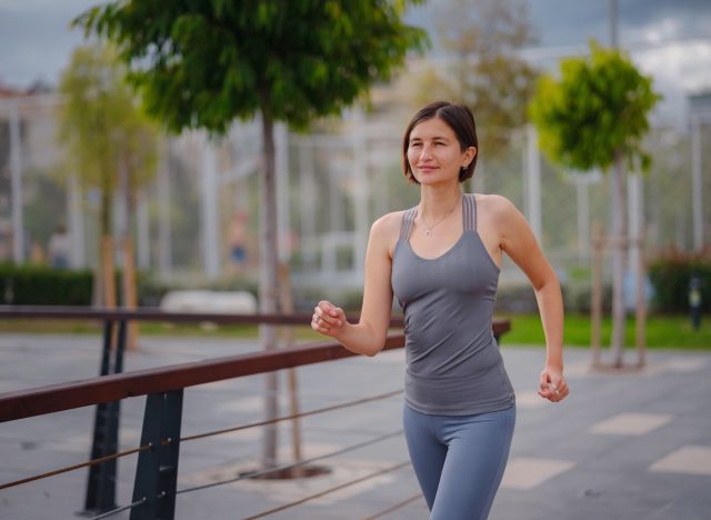 fit woman performing outdoor 15-minute walking workout to slim down and get toned