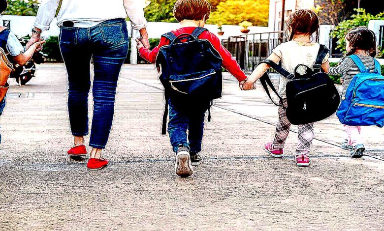 mom holding hands of kids as they walk to school
