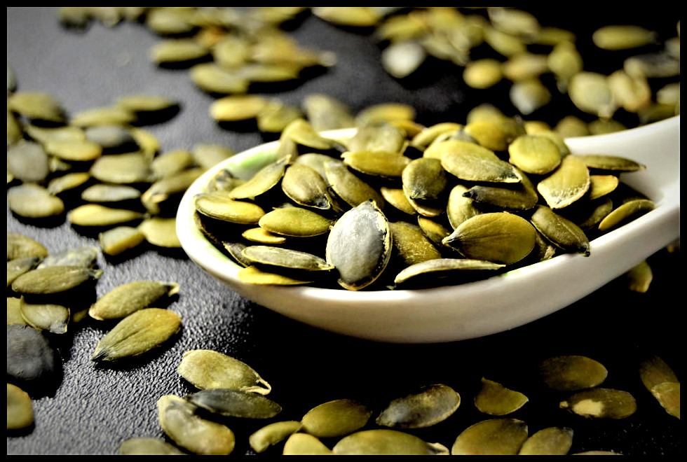 Pumpkin seeds in a bowl and on a table.